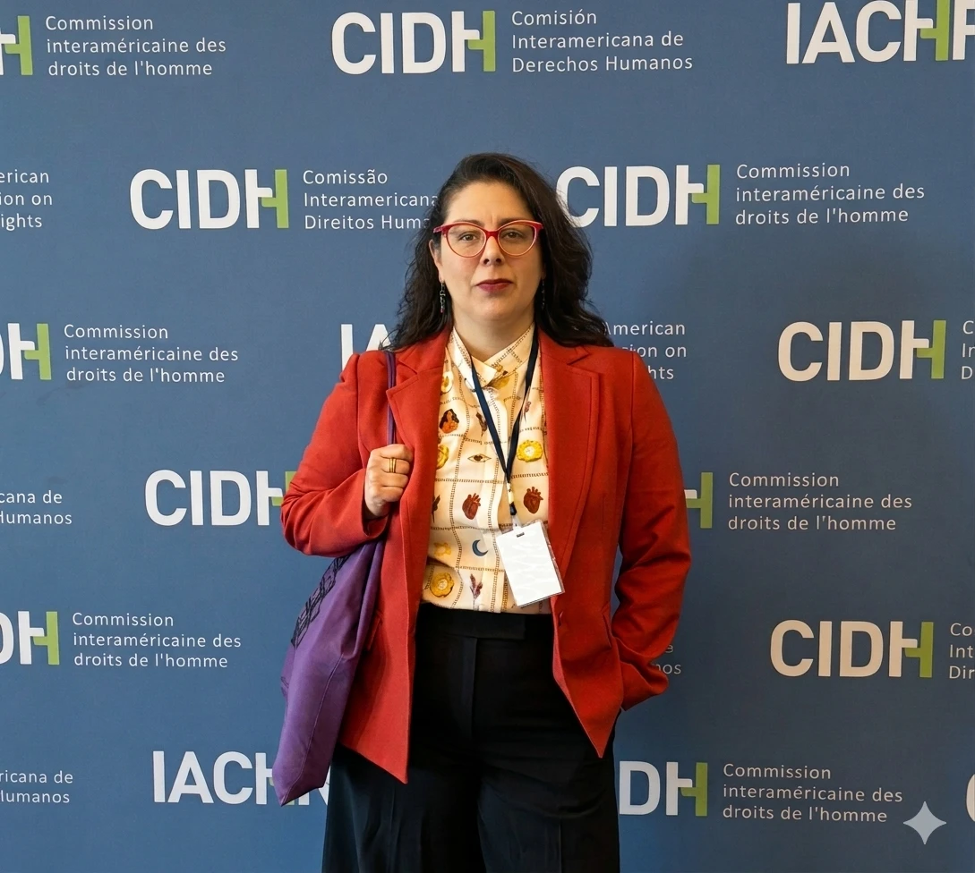Tamara Gonsalves standing and smiling in a large assembly hall (UN) with identification plaques and decorative ceiling.